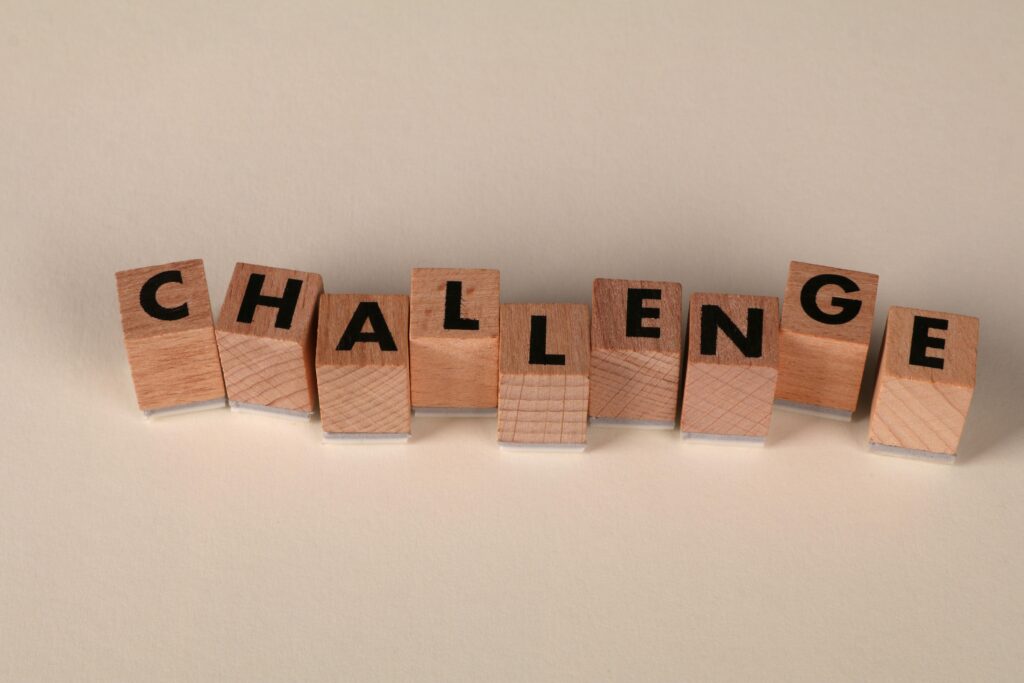 Wooden blocks arranged to spell 'Challenge' against a neutral backdrop, symbolizing overcoming obstacles.